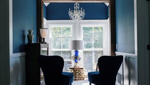 A room with two chairs facing a large window with a chandelier above. - The Granville Affair (Bridgetown)