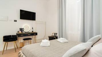 Ein modernes Hotelzimmer mit einem Bett, einem Schreibtisch mit Spiegel, einem Sessel und einem an der Wand befestigten Fernseher.