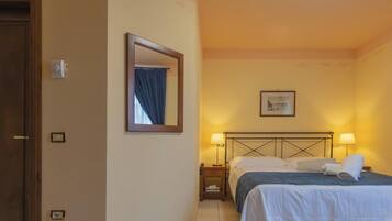Une chambre d’hôtel avec un lit, des lampes de chevet, une table de chevet, un miroir et un tableau encadré au mur.