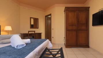 Une chambre d’hôtel comprenant un lit, un bureau, une chaise, une armoire et un téléviseur.