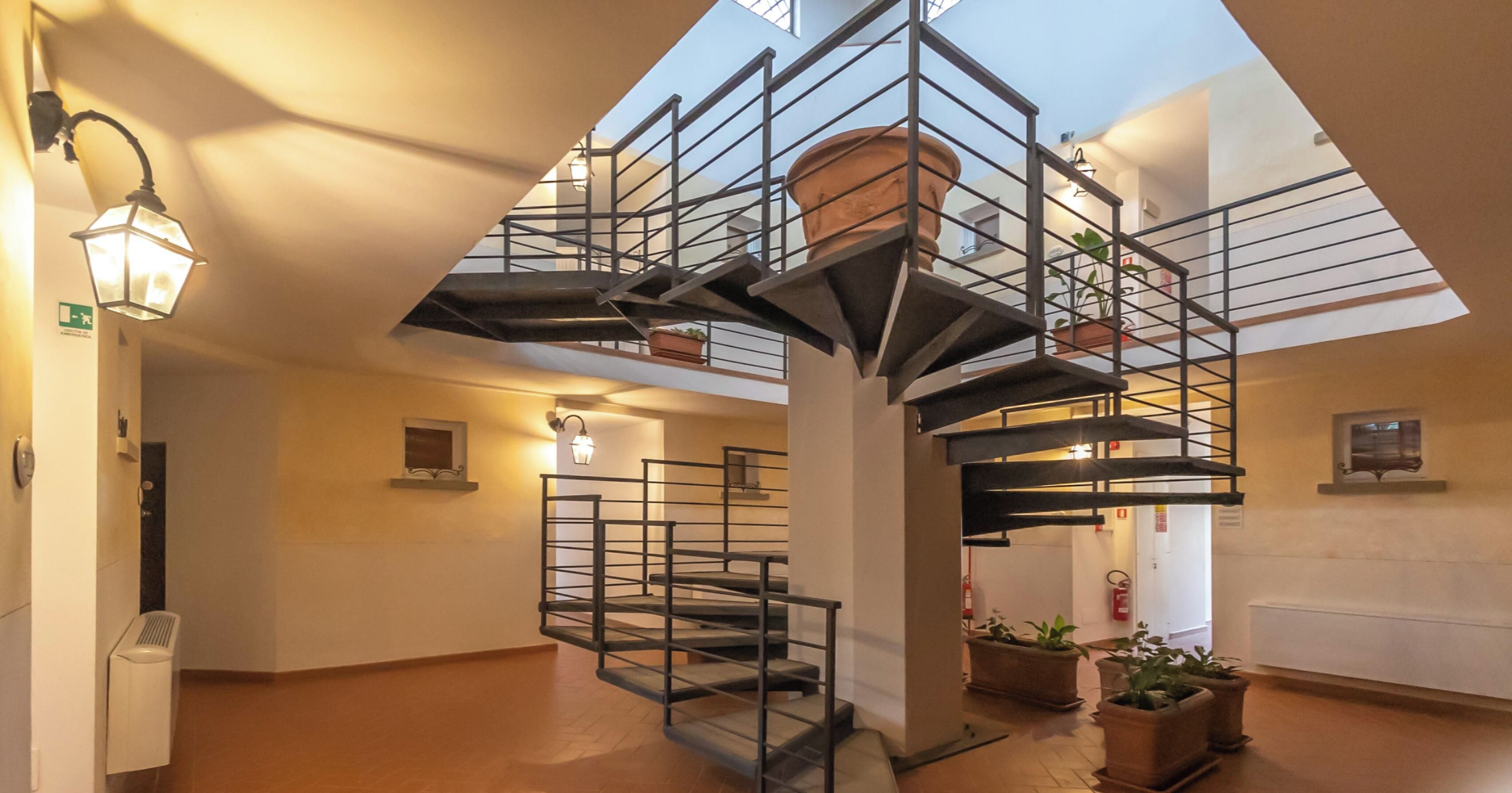 Un escalier en colimaçon au design moderne, agrémenté de plantes en pot et de luminaires fixés au mur.