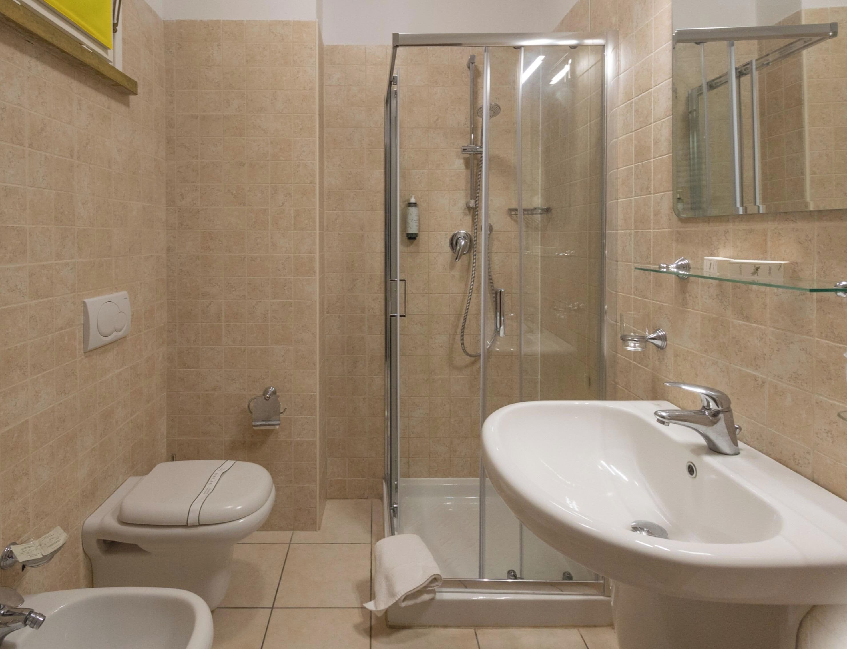 Ein Badezimmer mit Toilette, Bidet, Waschbecken und einer Duschkabine.