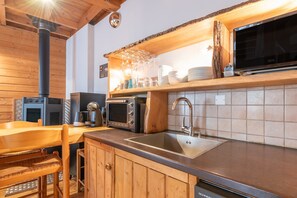 A kitchen with wooden cabinets, a sink, a microwave, a toaster, and a stove. - Central Luz-Saint-Sauveur Cottage with Mountain View and Wi-Fi (Luz-Saint-Sauveur)