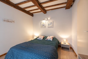 A bedroom with a bed, two bedside tables with lamps, wooden beams on the ceiling, and two wall-mounted artworks. - Central Luz-Saint-Sauveur Cottage with Mountain View and Wi-Fi (Luz-Saint-Sauveur)