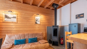 Interior de una cabaña de madera con sofá, chimenea, mesa y sillón.