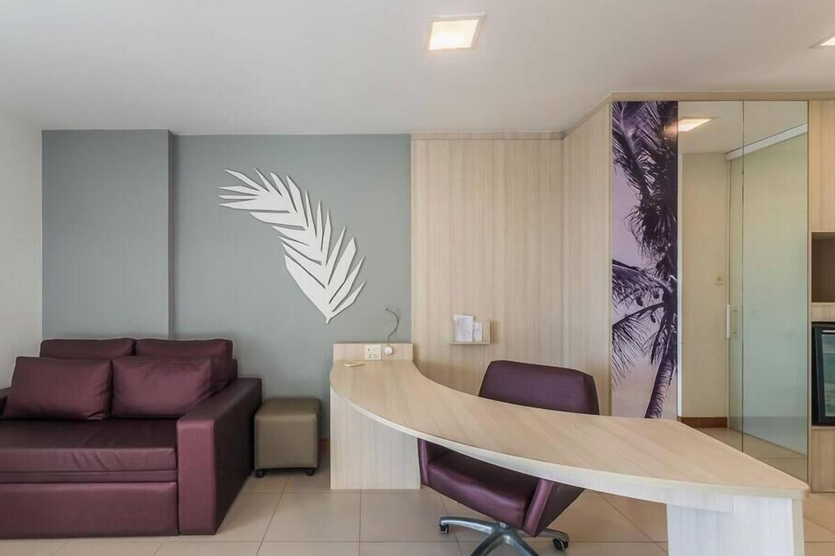Ein modernes Büro mit einem gebogenen Schreibtisch, einer Couch und einer Wanddekoration aus Blättern.