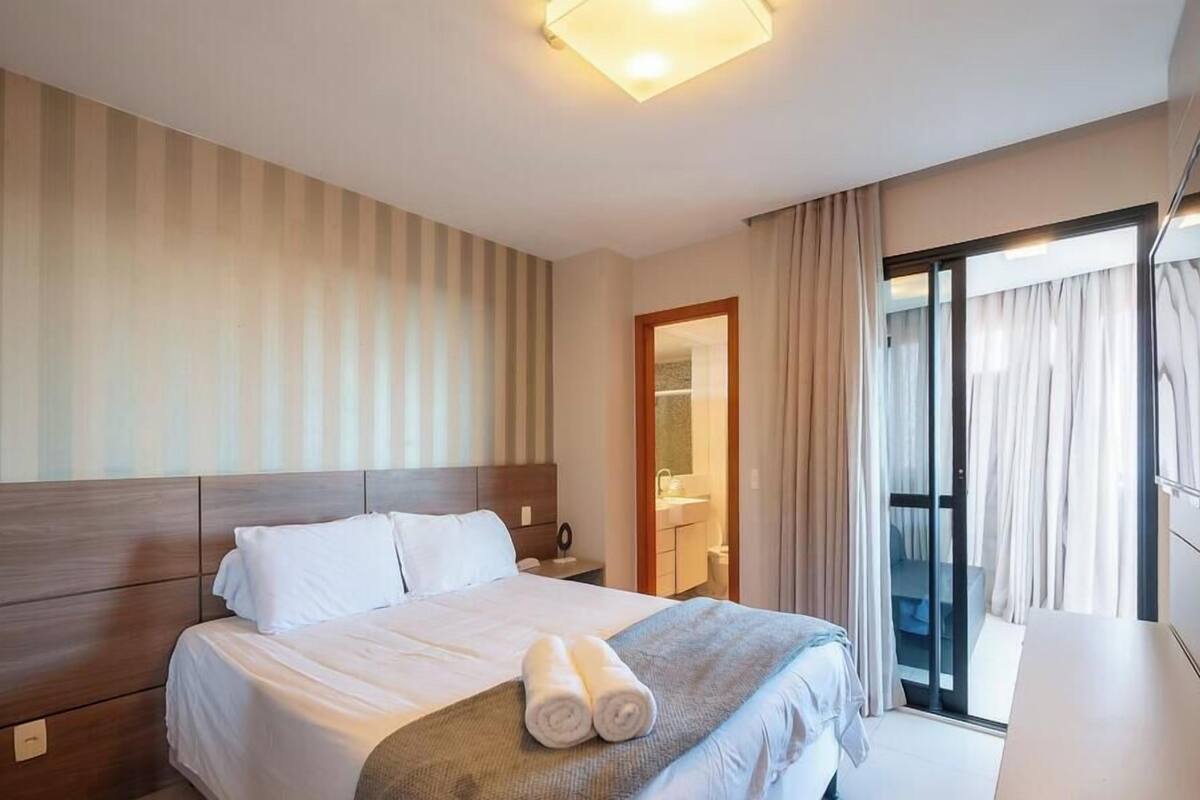 Ein Hotelzimmer mit Bett, Nachttisch, Spiegel und einer Schiebetür zum Balkon.