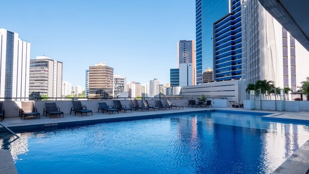 A rooftop pool with lounge chairs, surrounded by high-rise buildings. - Units at Salvador Boulevard Hotel - Msbs (Salvador)