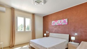 A bedroom with a large bed, a nightstand, a bedside table, a window with curtains, and a wall-mounted artwork. - PANORAMA - Elegant villa in a panoramic position! (Floridia)