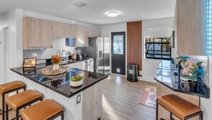 Une cuisine moderne dotée d’un îlot central, d’appareils électroménagers en acier inoxydable et de meubles en bois.