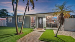 Une maison moderne à deux étages, dotée d’une pelouse bien entretenue, d’une allée pavée et d’une grande porte d’entrée vitrée.