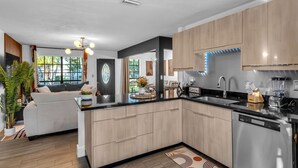 Une cuisine moderne avec des meubles en bois clair, un plan de travail noir et des appareils électroménagers en acier inoxydable.