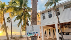 A beachside property with a sign reading "Slipstream 2.0" and a white building with a covered porch. - Slipstream 2.0 - A Modern Beachfront Escape (Long Island)