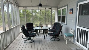 A covered porch with four striped chairs, a table, and a ceiling fan. - Spacious 5-bedroom "double house" in amazing Santa Rosa Beach with heated pool (Santa Rosa Beach)