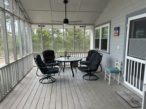 Eine überdachte Veranda mit vier gestreiften Stühlen, einem Tisch und einem Deckenventilator.