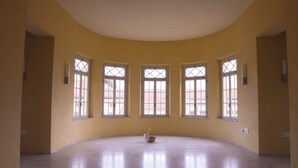 Ein geräumiger Raum mit gewölbter Decke und fünf großen Fenstern mit Kreuzmustern.