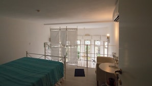 Ein Schlafzimmer mit Bett, Stuhl und einem Balkon mit Blick.