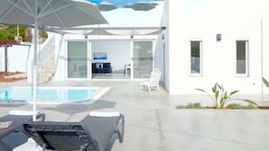 Uma casa moderna com piscina, área de estar externa e porta de vidro que dá para um pátio.