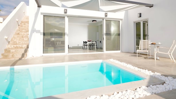 Uma casa moderna com piscina, varanda coberta e escada para o andar superior.