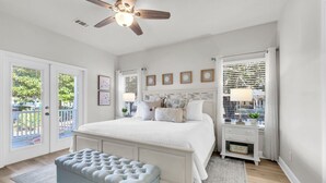 A bedroom with a bed, a ceiling fan, a nightstand, a bench, and a window with blinds. - Remodeled & New to VRBO 2026! Crystal Beach,Community pool, 3 blocks to beach (Destin)
