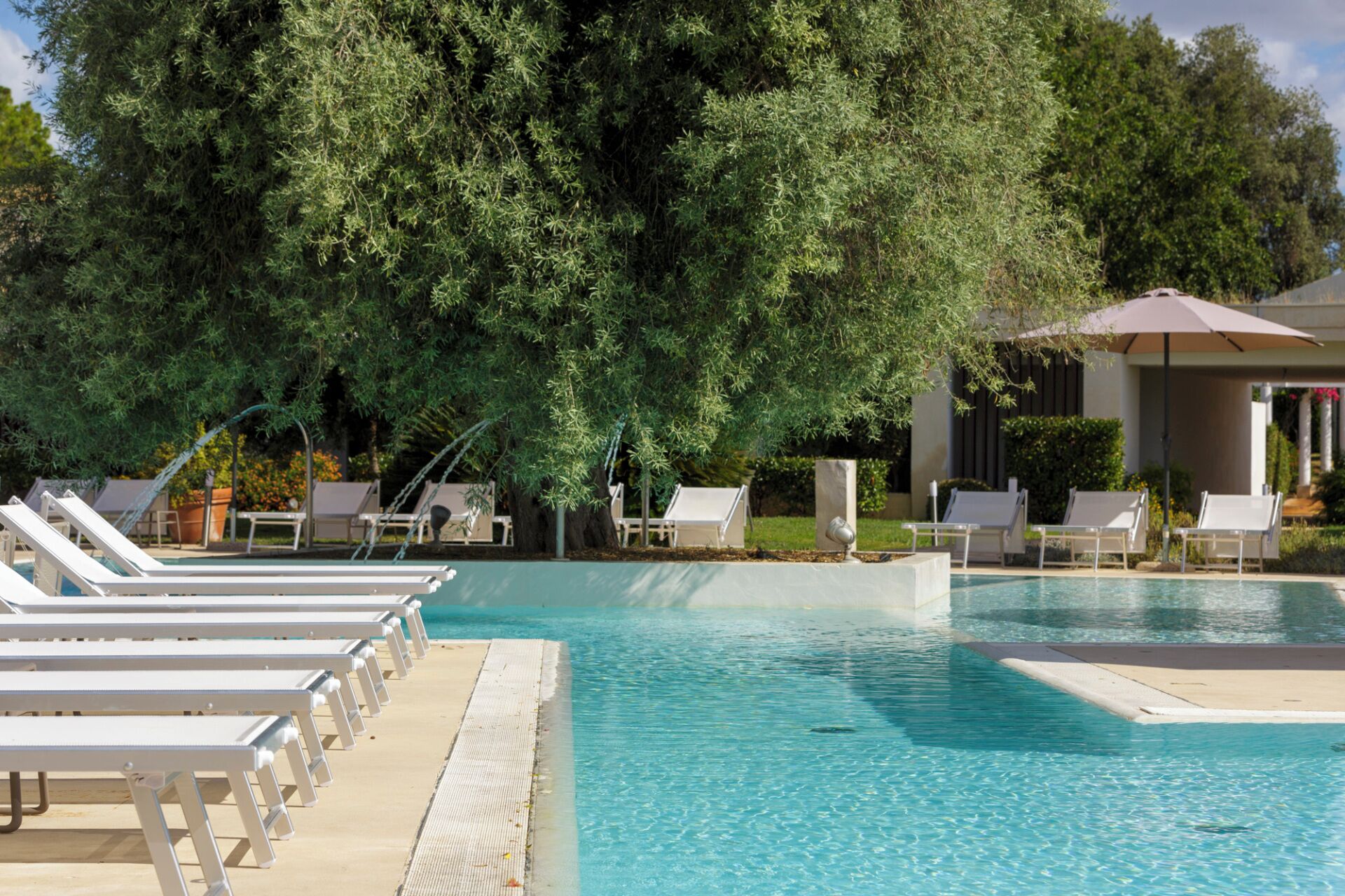 A pool area with lounge chairs and a covered seating area.