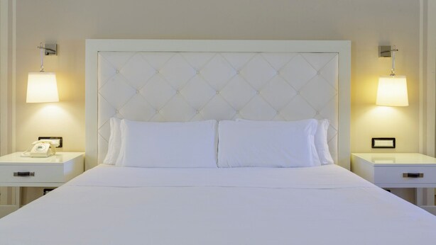 A hotel room with a large bed, two bedside tables, and two wall-mounted lamps. - Hotiday Siracusa Floridia (Syracuse)
