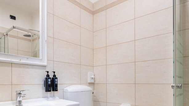Une salle de bain moderne avec un lavabo blanc, des toilettes et une douche à parois de verre.