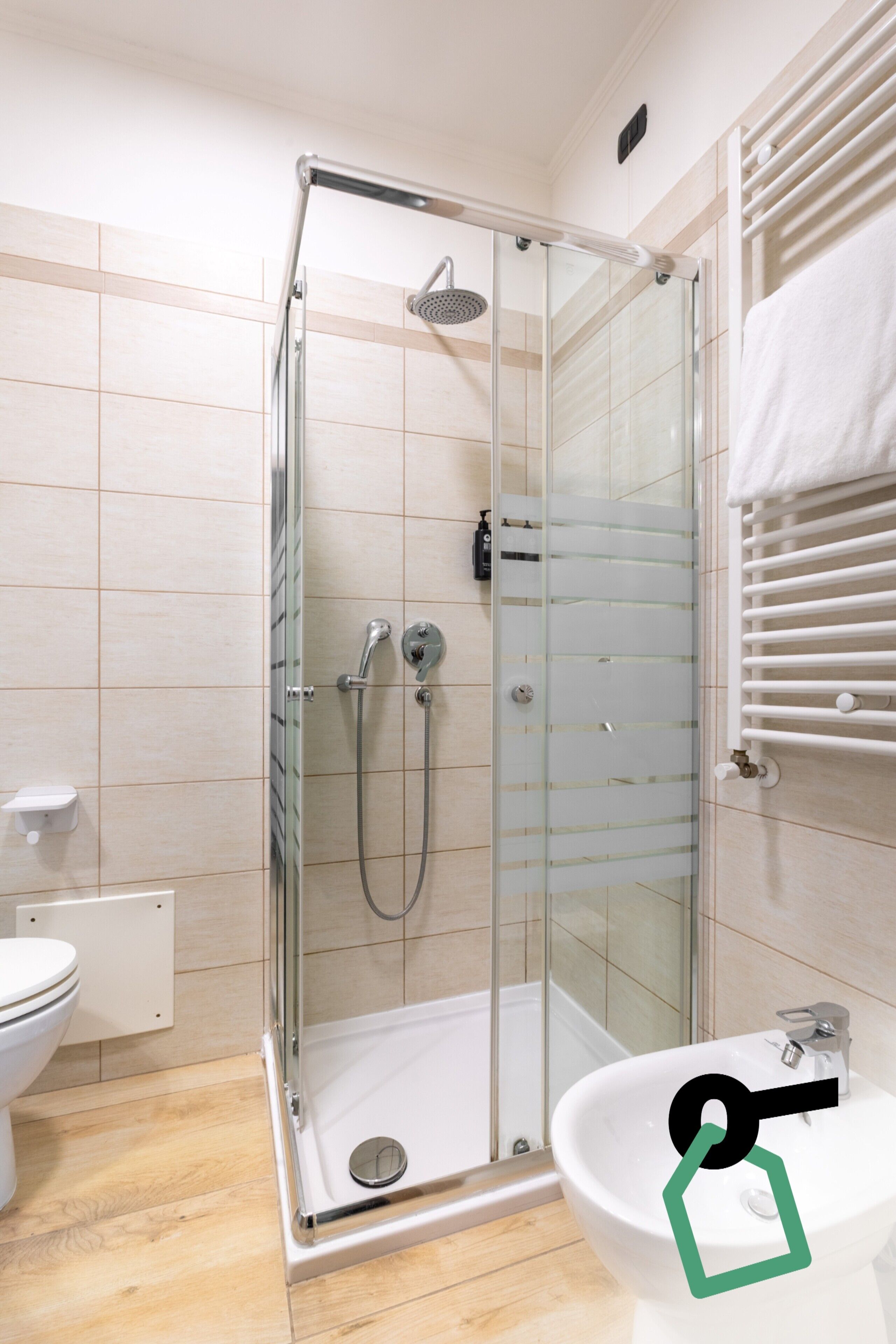 A modern bathroom with a glass-enclosed shower, a white sink, and a toilet.