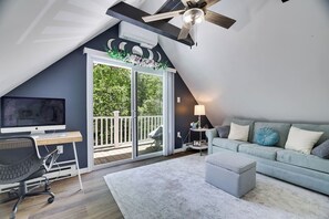 A modern loft bedroom with a large window, a ceiling fan, and a desk with a computer. - The Poconos Fun Chalet w/Game Room (Tobyhanna)