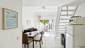 A modern kitchen with a white refrigerator, microwave, and a dining area with a table and chairs. - Mango Vert duplex with pool in Orient Bay! (Orient bay)