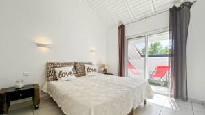 Une chambre à coucher avec un lit, des tables de chevet et une vue sur l’extérieur.