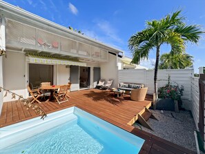 A backyard with a swimming pool, wooden deck, outdoor furniture, and a palm tree. - Mango Rouge, 2 bdr and private pool (Quarter of Orleans)