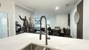 Eine Küche mit einem modernen Waschbecken, ein Essbereich mit Tisch und Stühlen sowie eine Wand mit einem Wandgemälde im Burgstil.