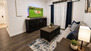 Ein Wohnzimmer mit Fernseher, dunklen Holzmöbeln, einer Couch und einem gemusterten Teppich.