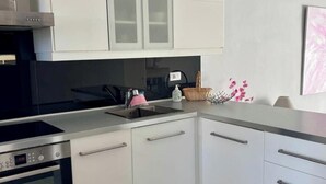 Eine moderne Küche mit weißen Schränken, einem Bosch-Ofen, einer Edelstahl-Dunstabzugshaube und einer Arbeitsplatte aus Granit.