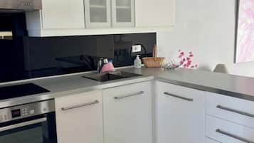 Una cocina moderna con armarios blancos, un horno Bosch, una campana extractora de acero inoxidable y una encimera de granito.