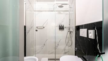 Een moderne badkamer met een douche met glazen wand, witte marmeren wanden en een accentmuur van zwart marmer.