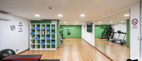 Un gimnasio con equipo de ejercicio, un espejo grande y una pared con citas motivacionales.