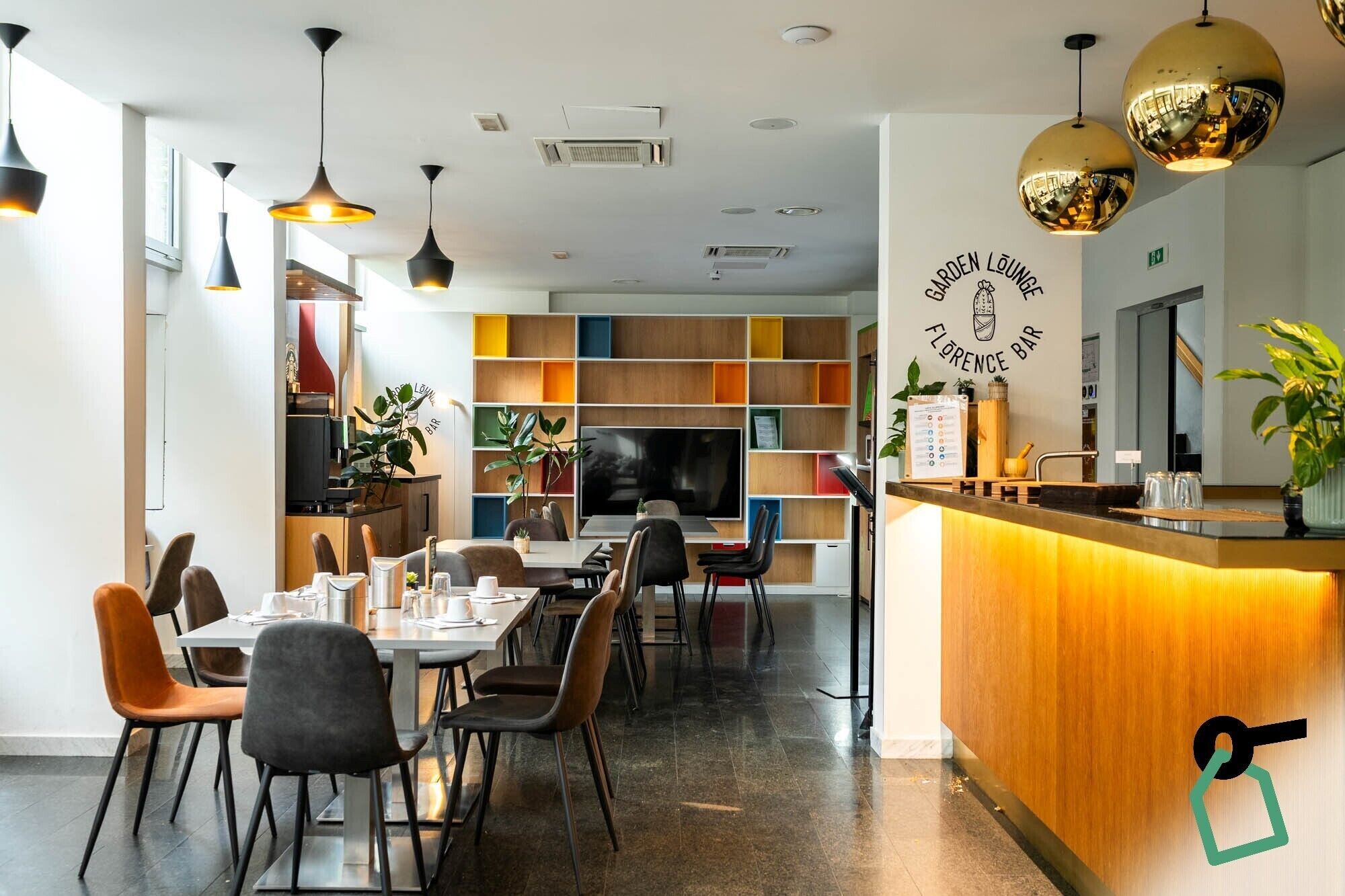 Zona de bar moderna con mostrador de madera, taburetes y una pantalla de televisión grande.