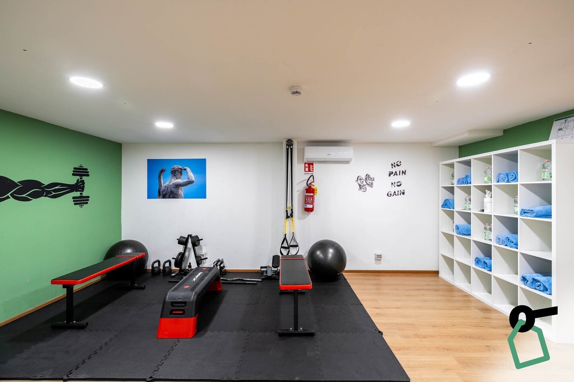 A gym with exercise equipment, a fire extinguisher, and a wall with motivational quotes.