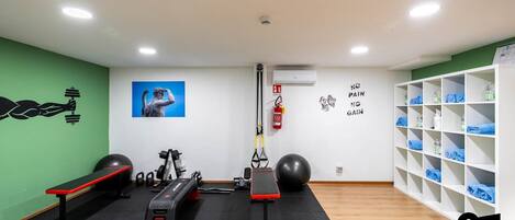 A gym with exercise equipment, a fire extinguisher, and a wall with motivational quotes.