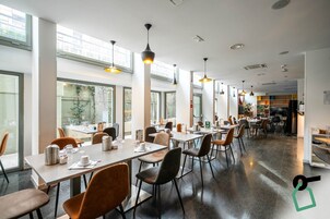 Un restaurante moderno con mesas largas, sillas e iluminación colgante.