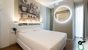 A hotel room with a large bed, a wall-mounted mirror, and a mural of a castle. - Hotiday Firenze Peretola (Florence)