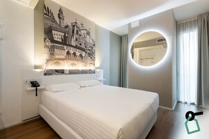 Una habitación de hotel con una cama grande, un espejo fijado a la pared y un mural de un castillo.