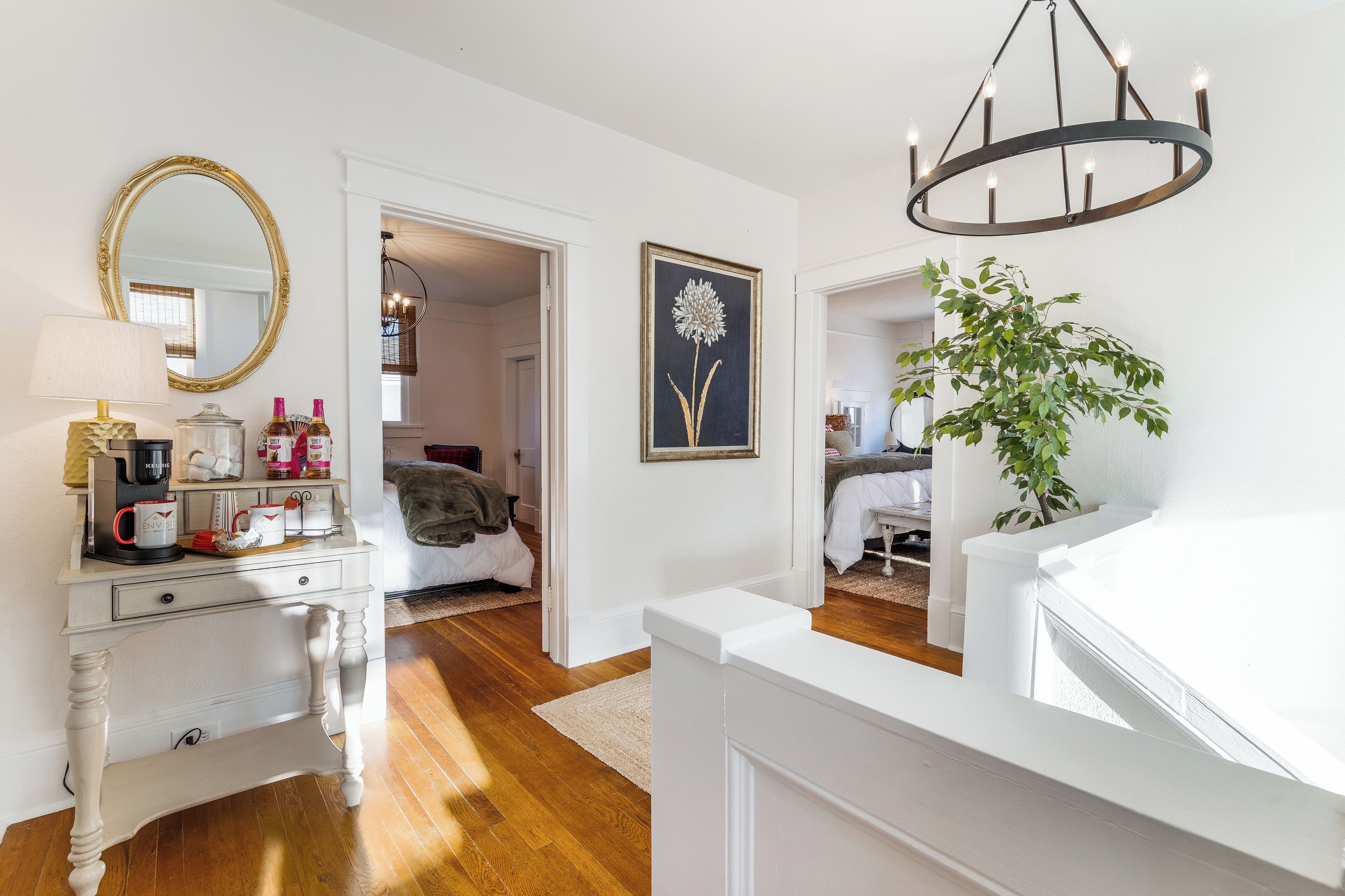 Een slaapkamer met een witte dressoir, een spiegel, een kroonluchter en een potplant.