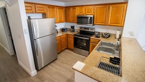 A modern kitchen with wooden cabinets, stainless steel appliances, and a granite countertop. - Orlando Blue Heron Condo Apt one Mile From Disney 12th floor (Orlando)