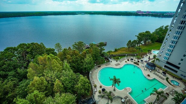 A hotel with a swimming pool, surrounded by lush greenery and a view of a large body of water. - Orlando Blue Heron Condo Apt one Mile From Disney 12th floor (Orlando)