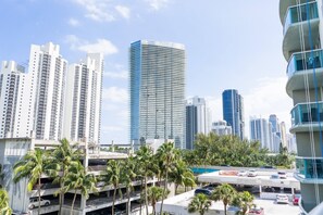A high-rise urban area with modern buildings, a parking structure, and palm trees. - Sunny Isles ocean-view 1BR: balcony, pool + gym, steps to beach (Sunny Isles Beach)