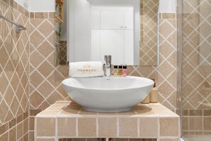 A bathroom with a large, round sink, a towel with 'TURNKEY DEL SOL' branding, and a mirror above the sink. - Residence Velora Bay Estepona (Estepona)