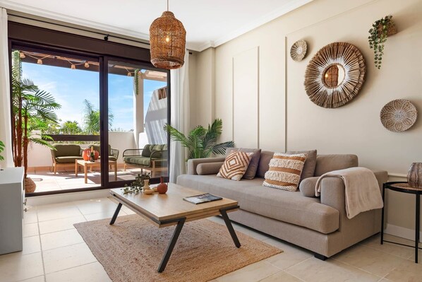 A modern living room with a sofa, coffee table, and decorative wall art. - Residence Velora Bay Estepona (Estepona)